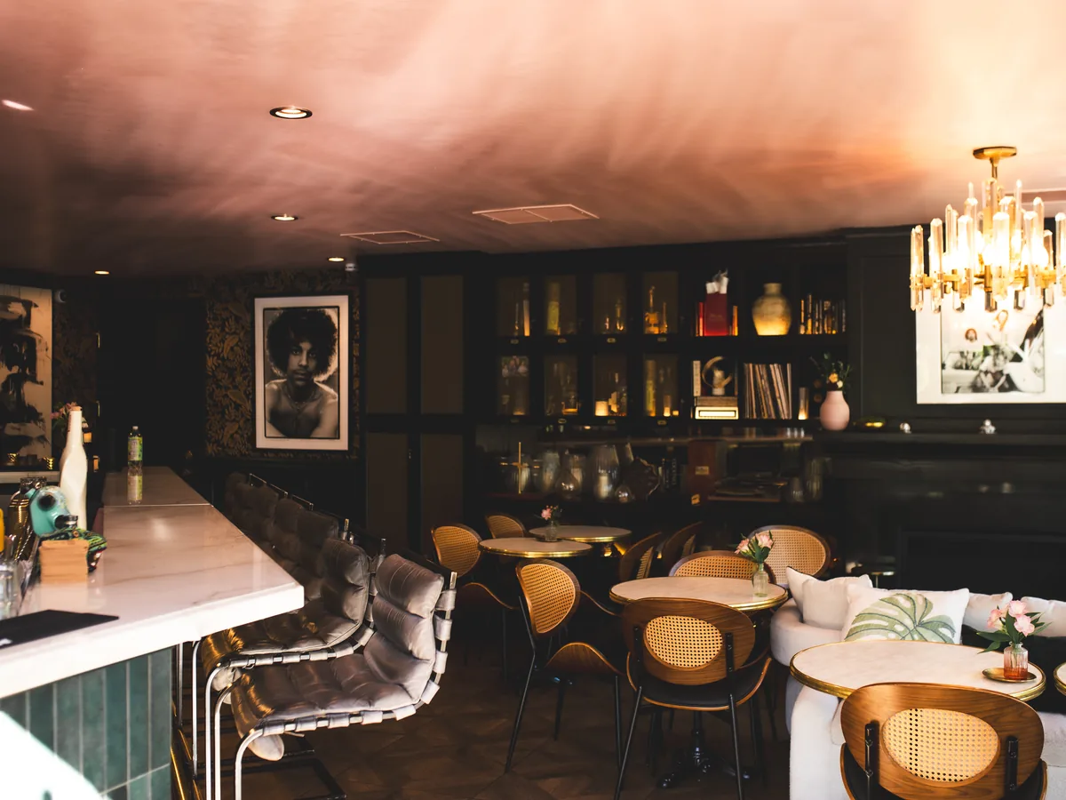 ASA's marble bar counter beneath the chandelier, stools ready for guests