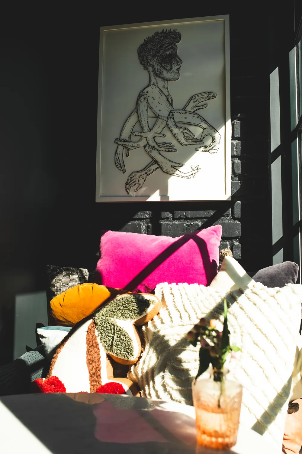 A sunlit lounge corner at ASA — framed line art above a bench of velvet pillows